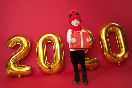 红色2020鼠年摄影照片_可爱的小男孩拿着新年礼物