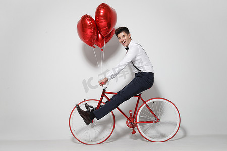 浪漫气球礼物摄影照片_青年男人骑自行车