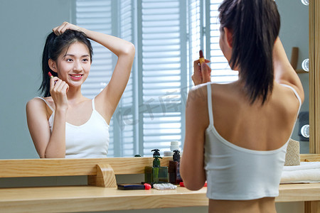 漂亮的年轻女人照着镜子梳头发