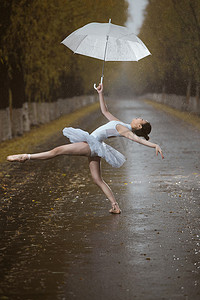 踮着脚尖摄影照片_拿着雨伞的青年女人跳芭蕾舞