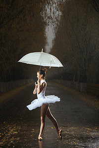 拿着雨伞的青年女人跳芭蕾舞