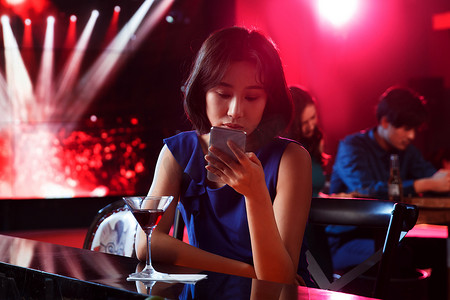 青年女人在酒吧看手机
