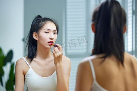 人像摄影照片_漂亮的年轻女人照着镜子涂口红