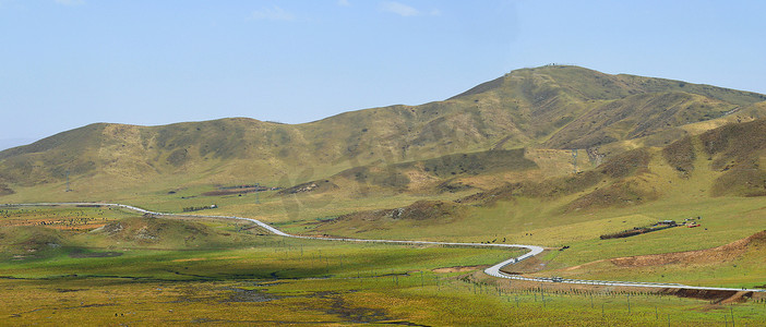 阳光下的草原山脉公路弯曲的乡间道路