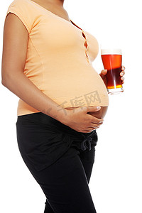 孕妇在她的肚子旁边拿着一杯酒