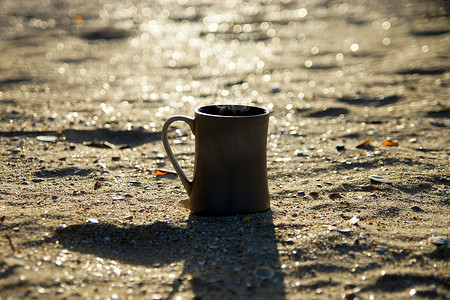 剪影咖啡杯摄影照片_早上在海滩上喝日出咖啡的剪影。