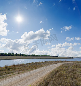 梦想阳光摄影照片_乡村路旁的河流和阴天天空中的阳光