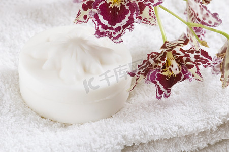 至关重要的摄影照片_带白毛巾、天然肥皂和兰花的水疗用品