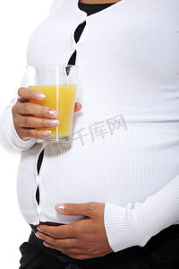 怀孕的女人拿着一杯橙汁