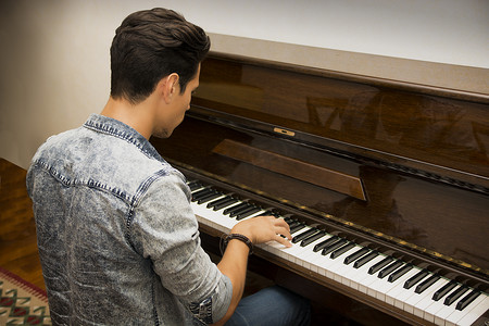 弹古典立式钢琴的年轻英俊的男性艺术家