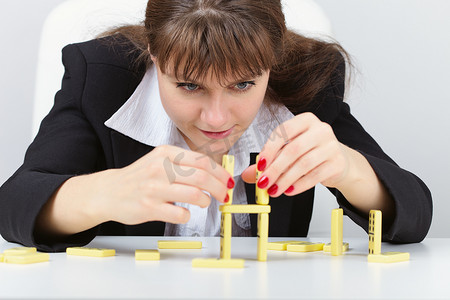 女人正专注于用多米诺骨牌在桌子上建一座塔