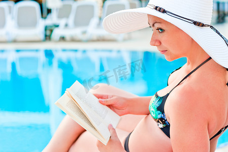 居泳池旁的比基尼女孩阅读书籍