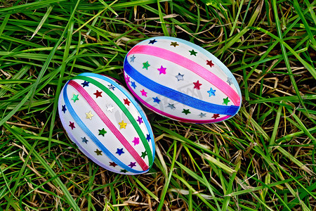 彩色春季摄影照片_彩带和亮片装饰的复活节彩蛋草地上