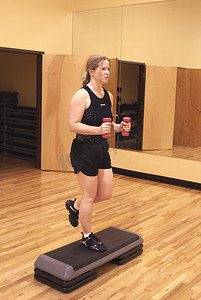 金发女人在健身房用手举重锻炼。