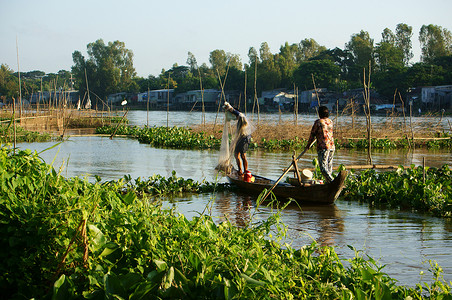 渔民划着小船在河上捕鱼