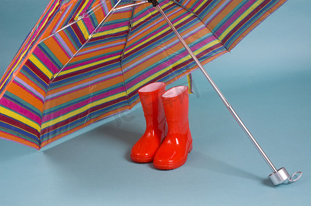 红色儿童雨靴和一把五颜六色的雨伞