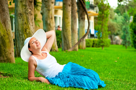 女孩戴着帽子在草坪上休息，仰望天空