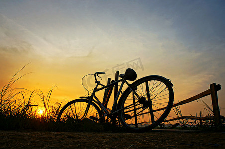 浪漫单车摄影照片_日出时自行车停在木栅栏上