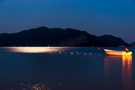 月亮夜晚背景摄影照片_夜晚的渔船平静的海面