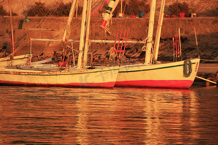 三桅小帆船摄影照片_卢克索日落时停在港口的三桅帆船