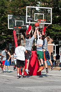 男子在街头篮球比赛中为球而战时跳跃