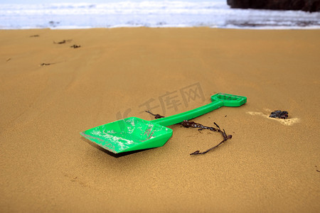 金铲摄影照片_海滩上的绿色塑料铲