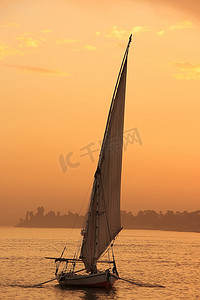 三桅小帆船摄影照片_Felucca 船在日落时在尼罗河上航行，卢克索