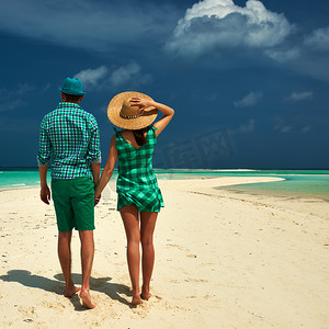 绿色衣服摄影照片_在马尔代夫的海滩上穿着绿色衣服的情侣