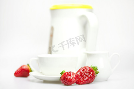白色杯子、牛奶罐、茶壶和草莓隔离在白色