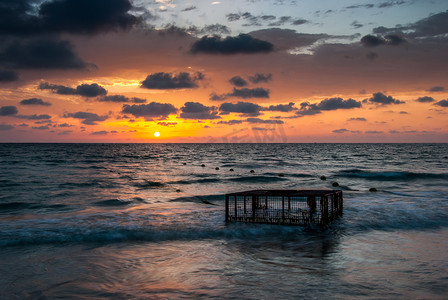 笼子摄影照片_热带海滩与日落时海中的空笼子