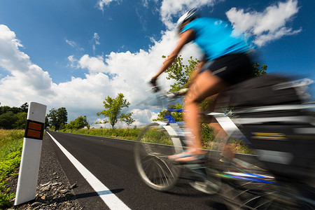 自明亮摄影照片_骑自行车在乡下公路的女性骑自行车者