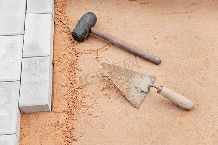 沙子上泥瓦匠的工具-抹子和锤子