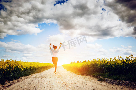 快乐的年轻女人向着太阳奔跑和跳跃