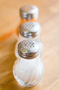 木桌上的摇瓶玻璃瓶中的盐和胡椒