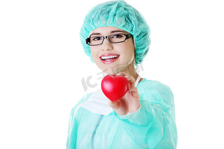 拿着红色心脏的微笑的女性医生或护士