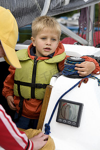 在游艇上穿着救生衣的可爱小男孩。