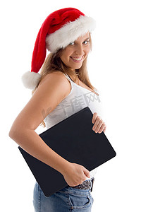 圣诞帽服装摄影照片_戴着圣诞帽和笔记本电脑的女人的侧姿