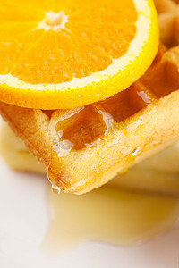比利时华夫饼、蜂蜜和橙子放在盘子里，与白色隔开