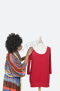 非裔美国女性时尚设计师在灰色背景下查看红色束腰外衣