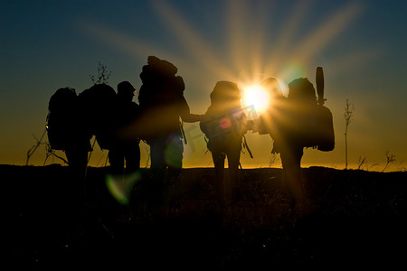 极限攀岩摄影照片_徒步远足者在黄昏时分沐浴阳光和倒影中行走