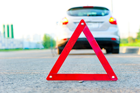 问题标志摄影照片_红色警告三角和一辆有紧急警报的汽车
