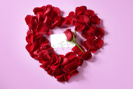 心形的花瓣摄影照片_心形红玫瑰花瓣，复制空间空白纸条