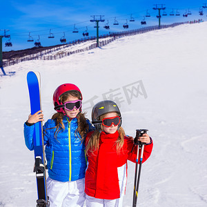 滑雪女孩子摄影照片_冬雪中的小女孩姐妹带着滑雪设备