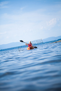 安全背心的女人独自在平静的海面上划皮划艇