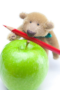 白色隔离的泰迪熊、苹果和彩色铅笔