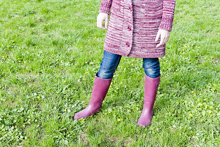 春天草地上穿橡胶靴的女人的细节