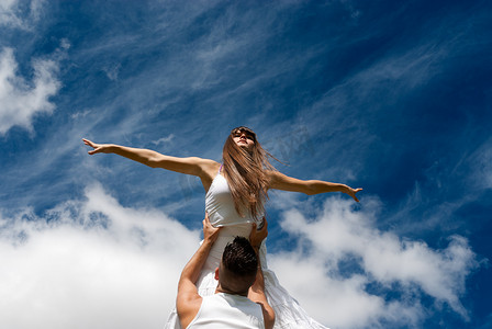 年轻夫妇在天空背景中跳舞，自由和放松的象征
