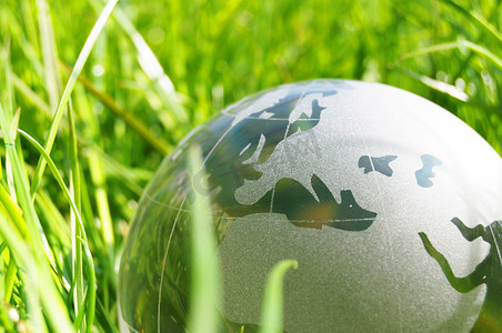 绿色玻璃球摄影照片_草地上的玻璃球或地球