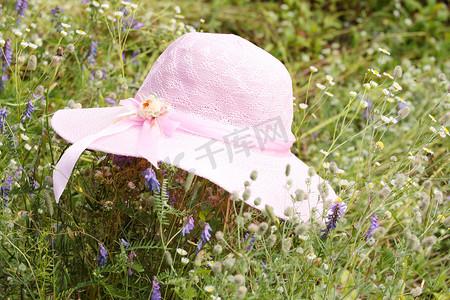 粉红色帽子摄影照片_一顶夏天的粉红色帽子躺在草地上