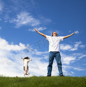 年轻人和他的狗在绿地上放松
